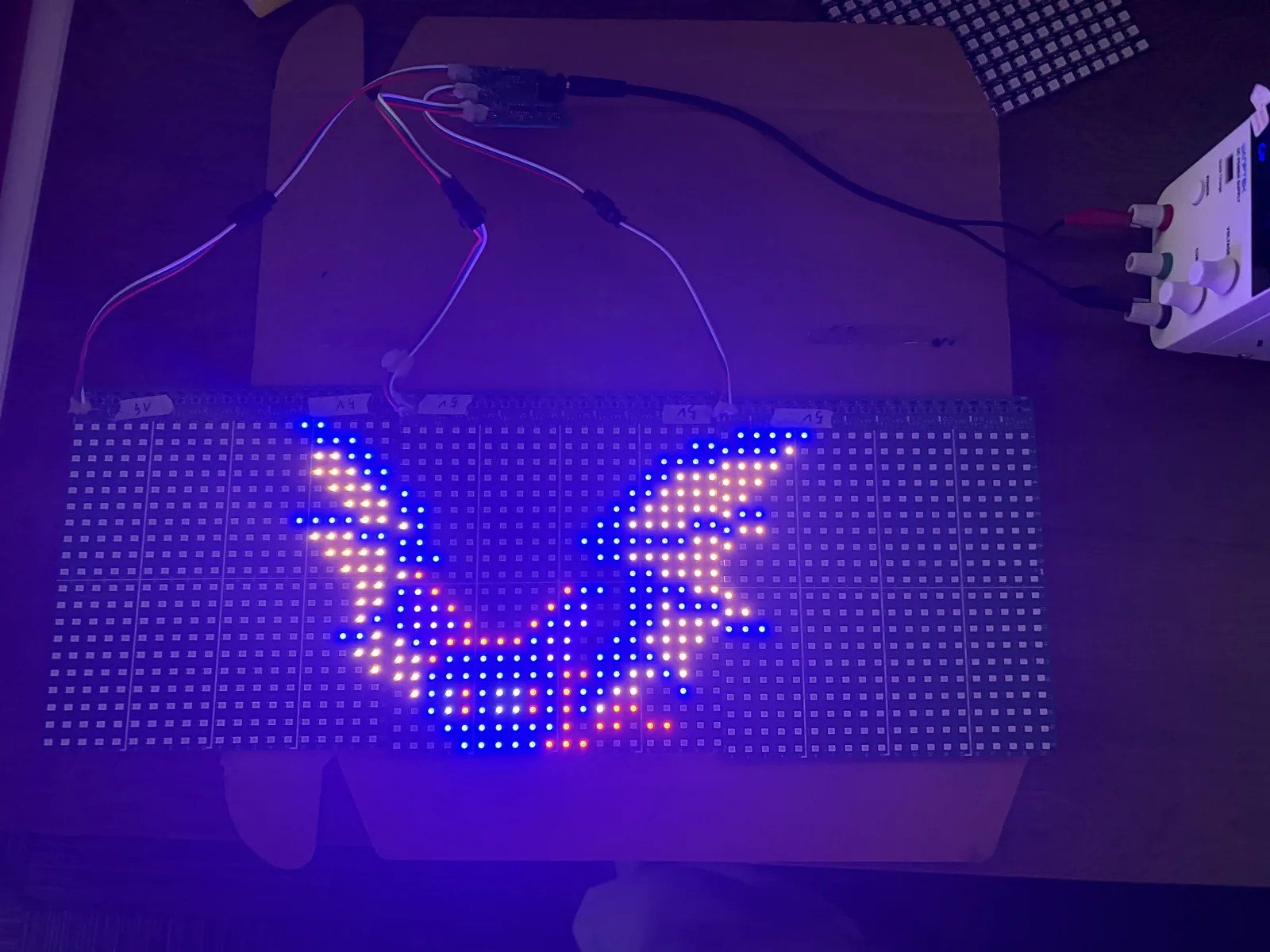 The same panel assembly displaying a different pixel graphic, with the image spanning several panels and the unlit portions of each panel visible around it.