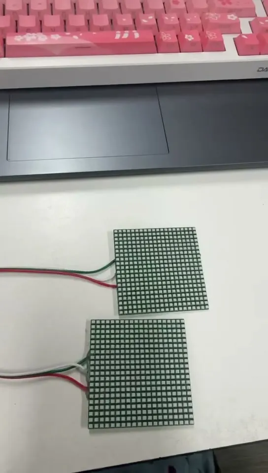 Two LED matrix panels switched off on a desk, showing the bare black grid of individual pixels.