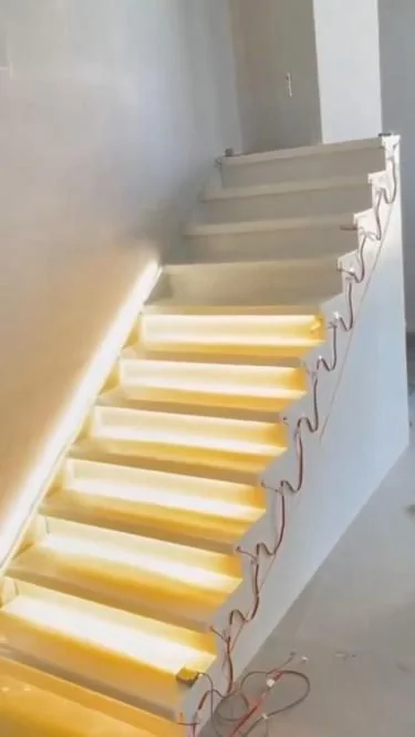 A staircase under construction with warm white LED strip fitted beneath each tread.