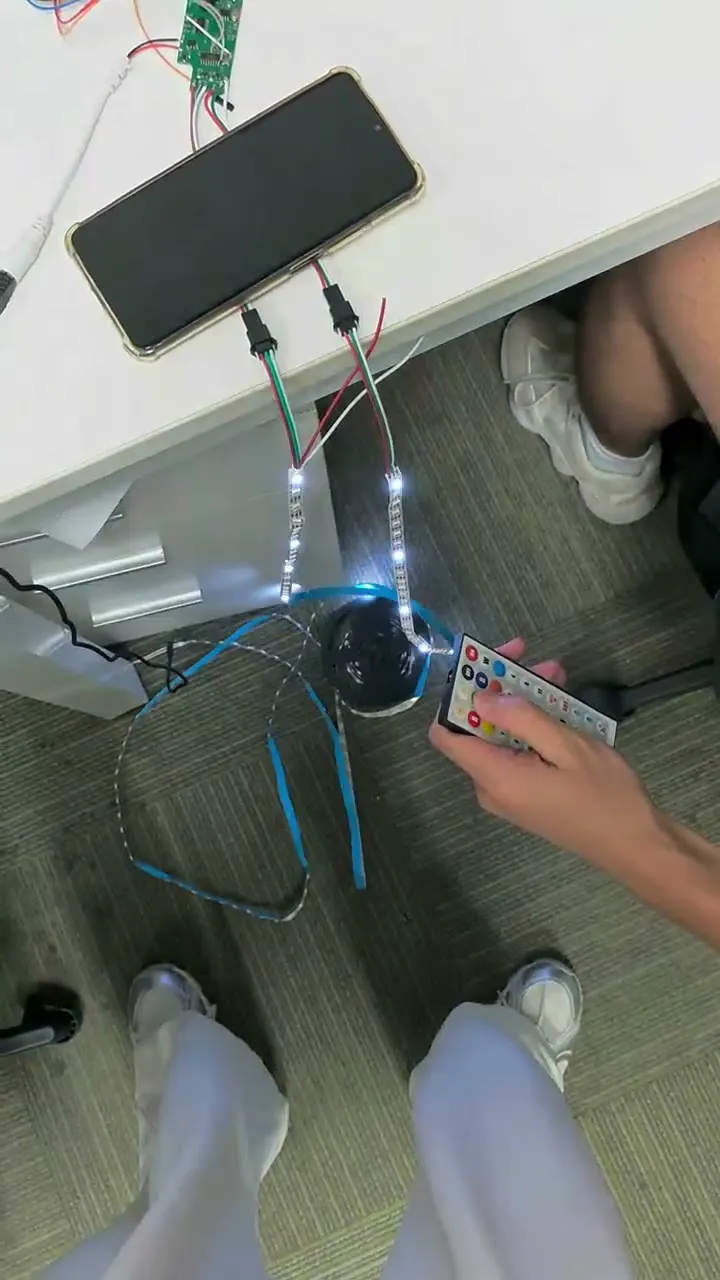 A fibre-optic LED strip coiled on the floor and lit blue, with a phone and a remote beside it.