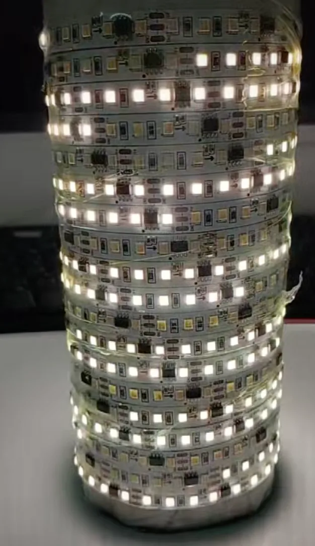 A reel of addressable LED strip powered up on a bench, close enough to see each white LED and the small driver chip sitting between them on the flexible board.