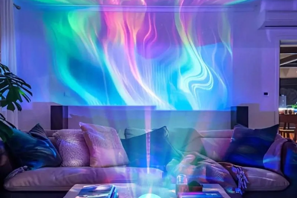 Aurora-style bands of pink, green and blue light from a star light washing across a living-room ceiling and wall.